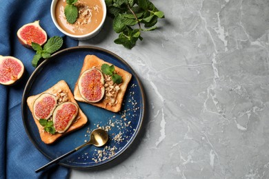 Photo of Tasty toasts served with fig, peanut butter and walnuts on light grey marble table, flat lay. Space for text