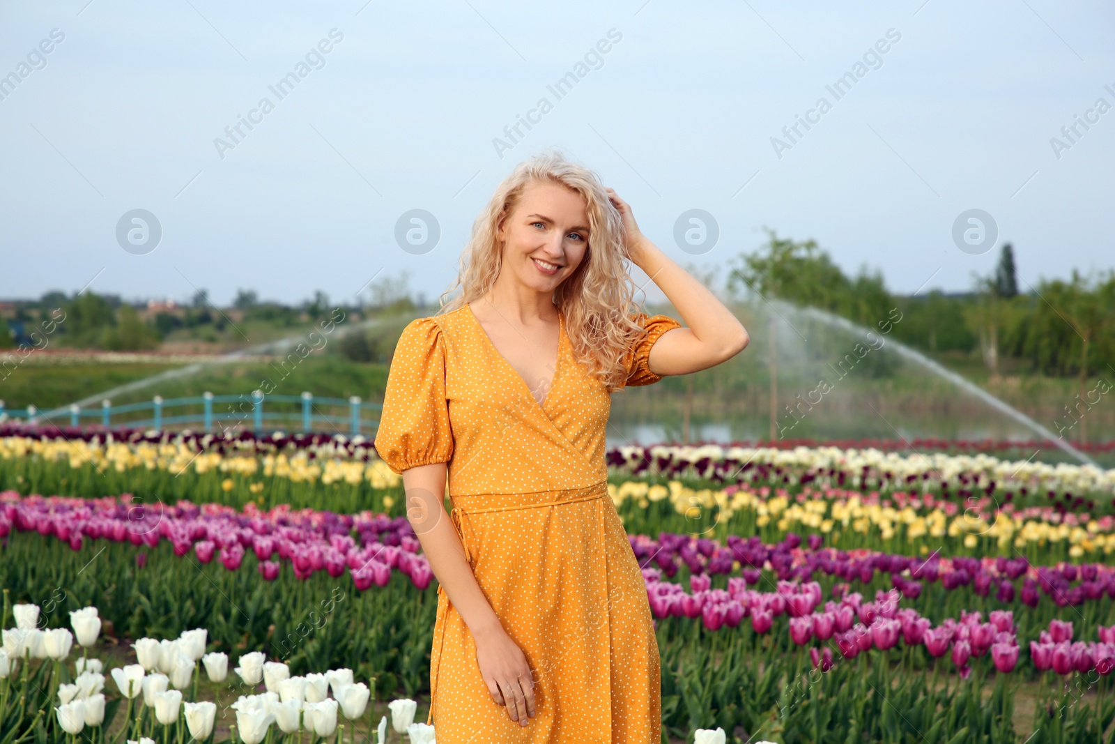 Photo of Happy woman in beautiful tulip field outdoors