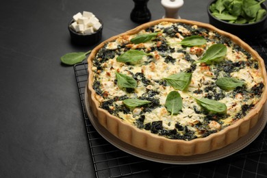 Delicious homemade spinach quiche on black table, closeup