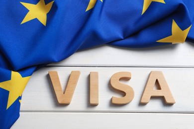Photo of Word Visa made of letters and European Union flag on white wooden table, flat lay