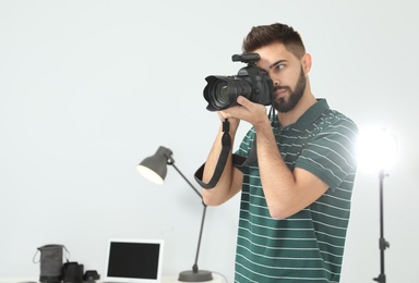 Photo of Young man with professional camera in photo studio