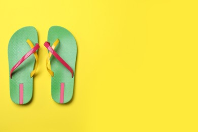 Stylish flip flops on yellow background, flat lay. Space for text