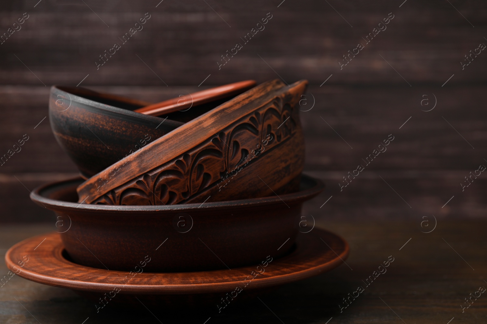 Photo of Set of clay dishes on wooden table, space for text. Cooking utensils