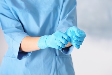 Photo of Doctor taking off medical gloves on color background