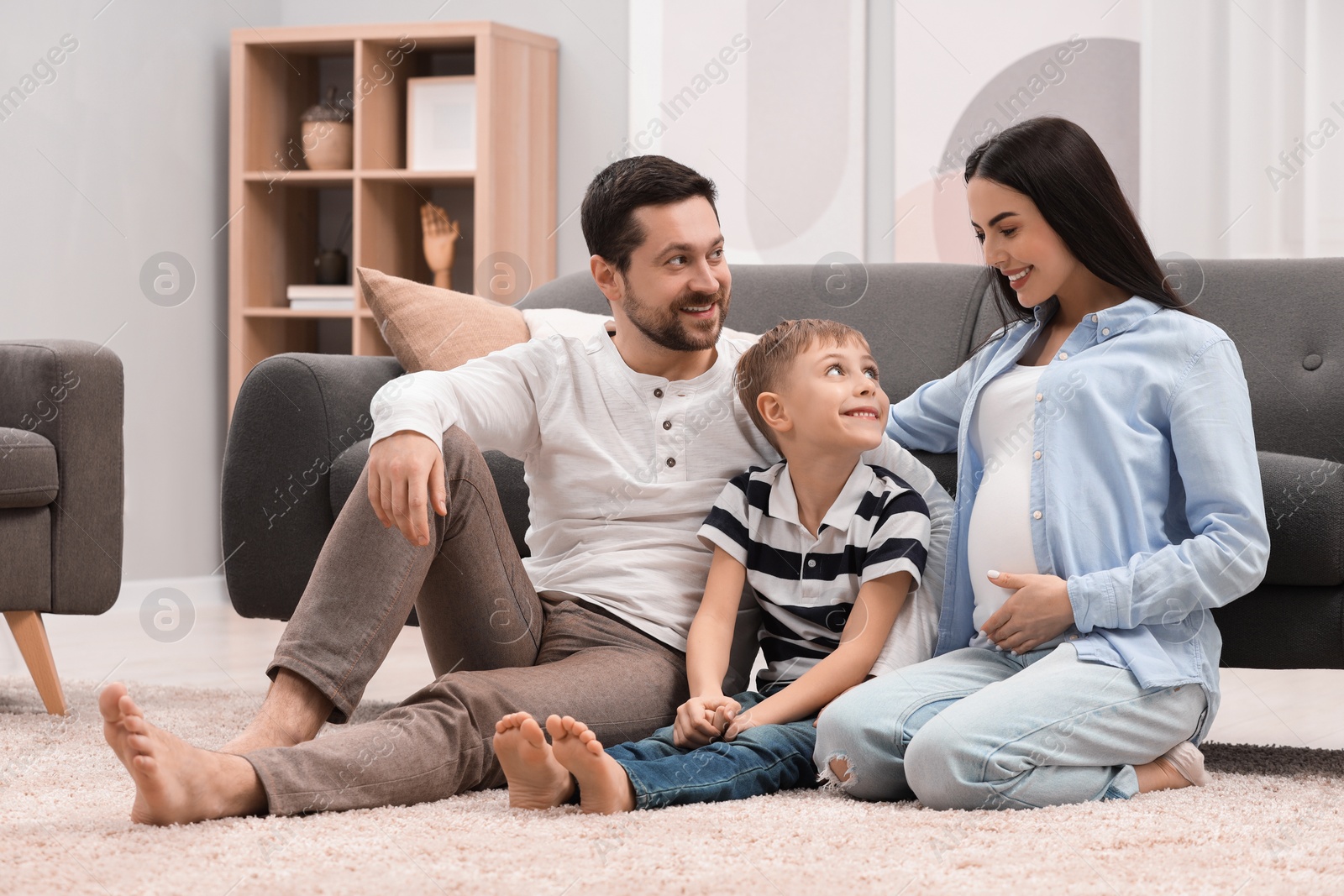 Photo of Pregnant woman spending time with her son and husband at home. Happy family