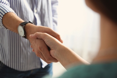 Photo of Man and woman shaking hands on light background, closeup. Help and support concept