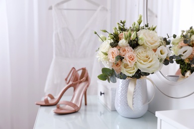 Photo of Beautiful wedding bouquet and shoes on dressing table indoors