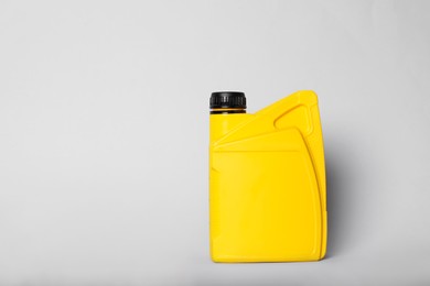 Photo of Motor oil in yellow canister on light background, space for text