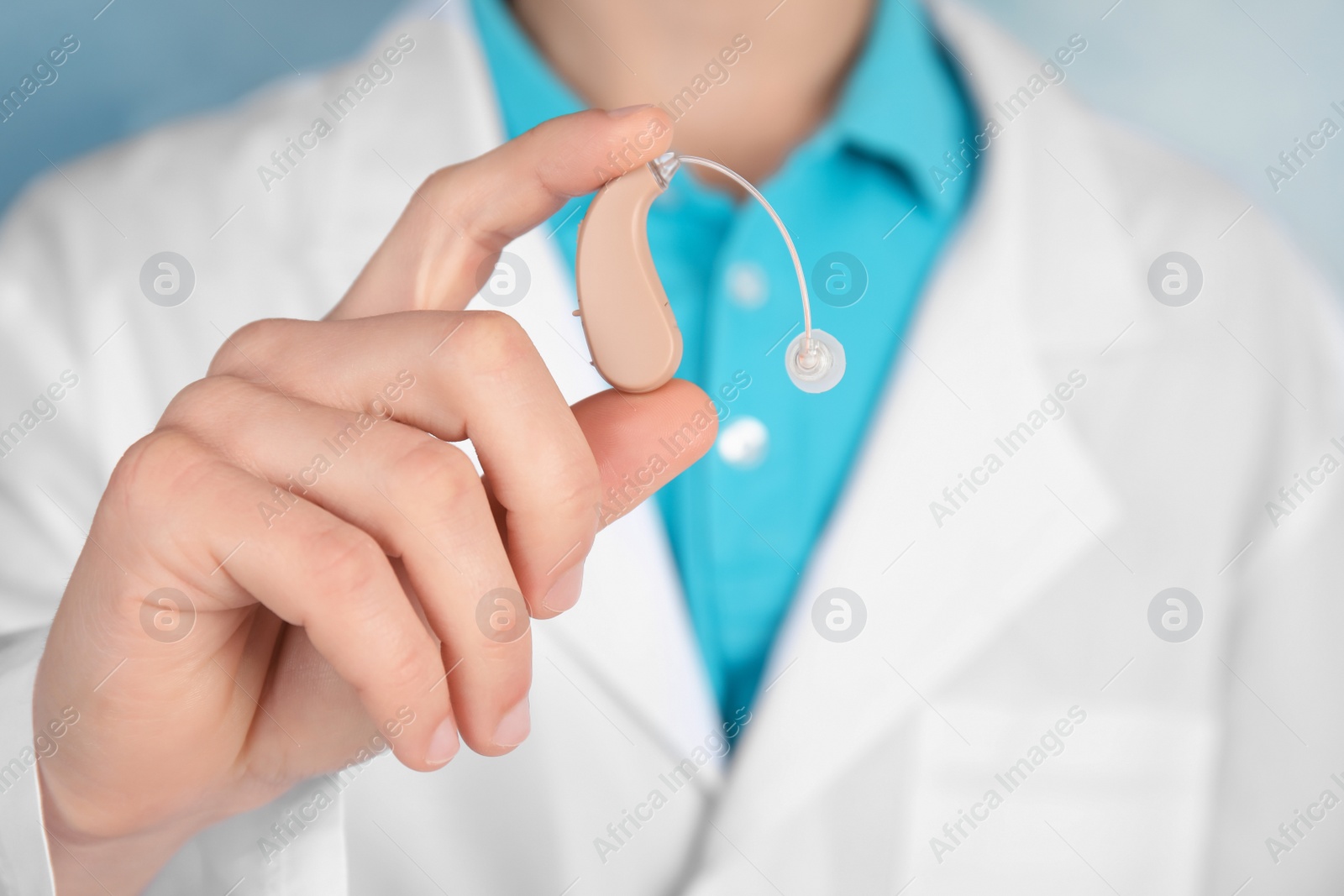 Photo of Doctor holding hearing aid, closeup. Medical device