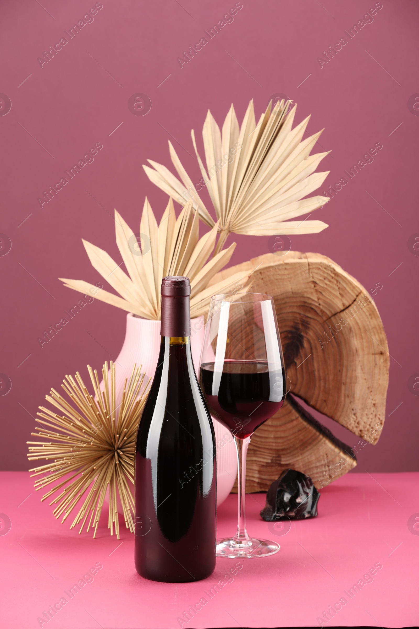 Photo of Stylish presentation of delicious red wine in bottle and glass on pink background