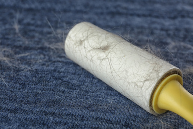 Lint roller on blue fabric covered with hair, closeup