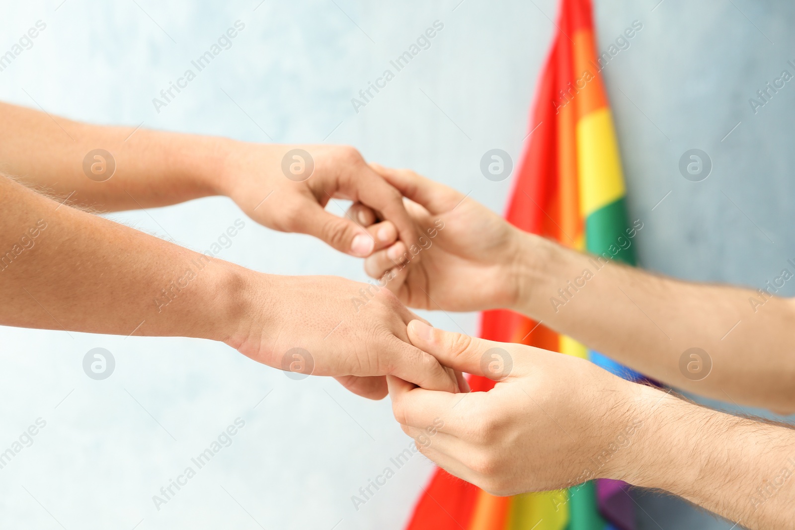 Photo of Gay couple holding hands near rainbow flag