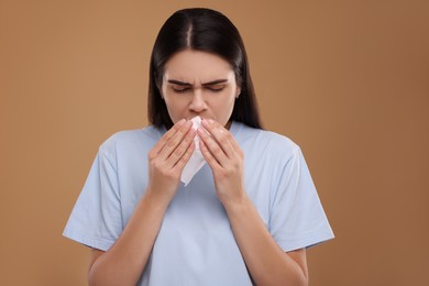 Photo of Woman with tissue coughing on brown background. Cold symptoms