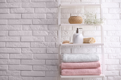 Photo of Clean towels on shelving unit in bathroom. Space for text