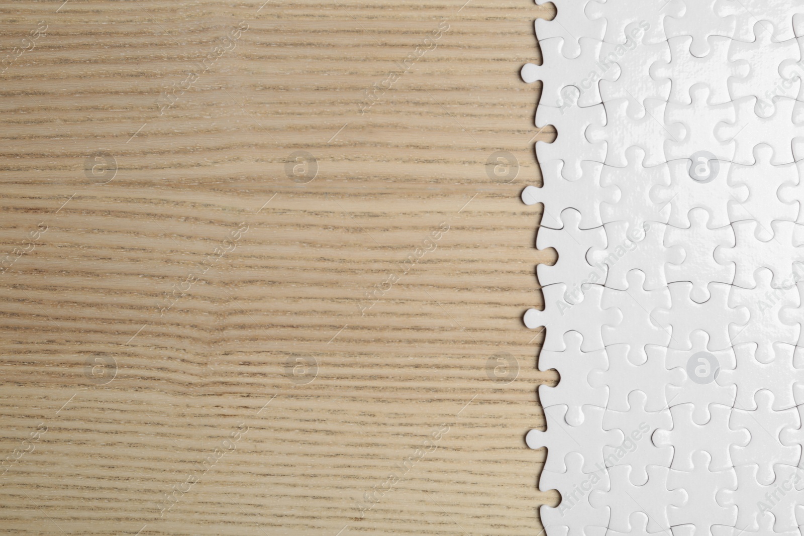 Photo of Blank white puzzle pieces on wooden background, flat lay. Space for text