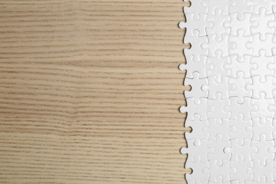 Photo of Blank white puzzle pieces on wooden background, flat lay. Space for text