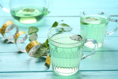 Photo of Herbal diet tea and measuring tape on light blue wooden table