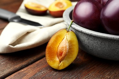 Photo of Tasty ripe plums on wooden table, closeup