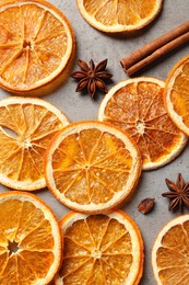 Photo of Dry orange slices, cinnamon sticks and anise stars on grey table, flat lay