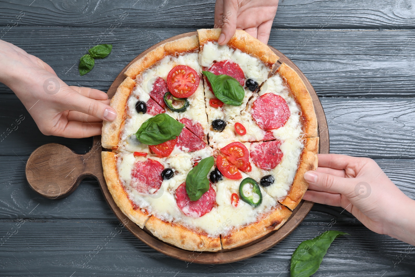 Photo of People taking pieces of delicious pizza Diablo at wooden table, top view