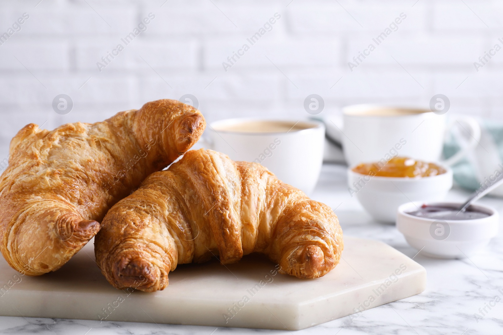 Photo of Tasty breakfast. Fresh croissants and jam on white marble table