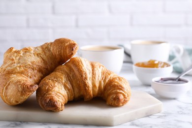 Photo of Tasty breakfast. Fresh croissants and jam on white marble table