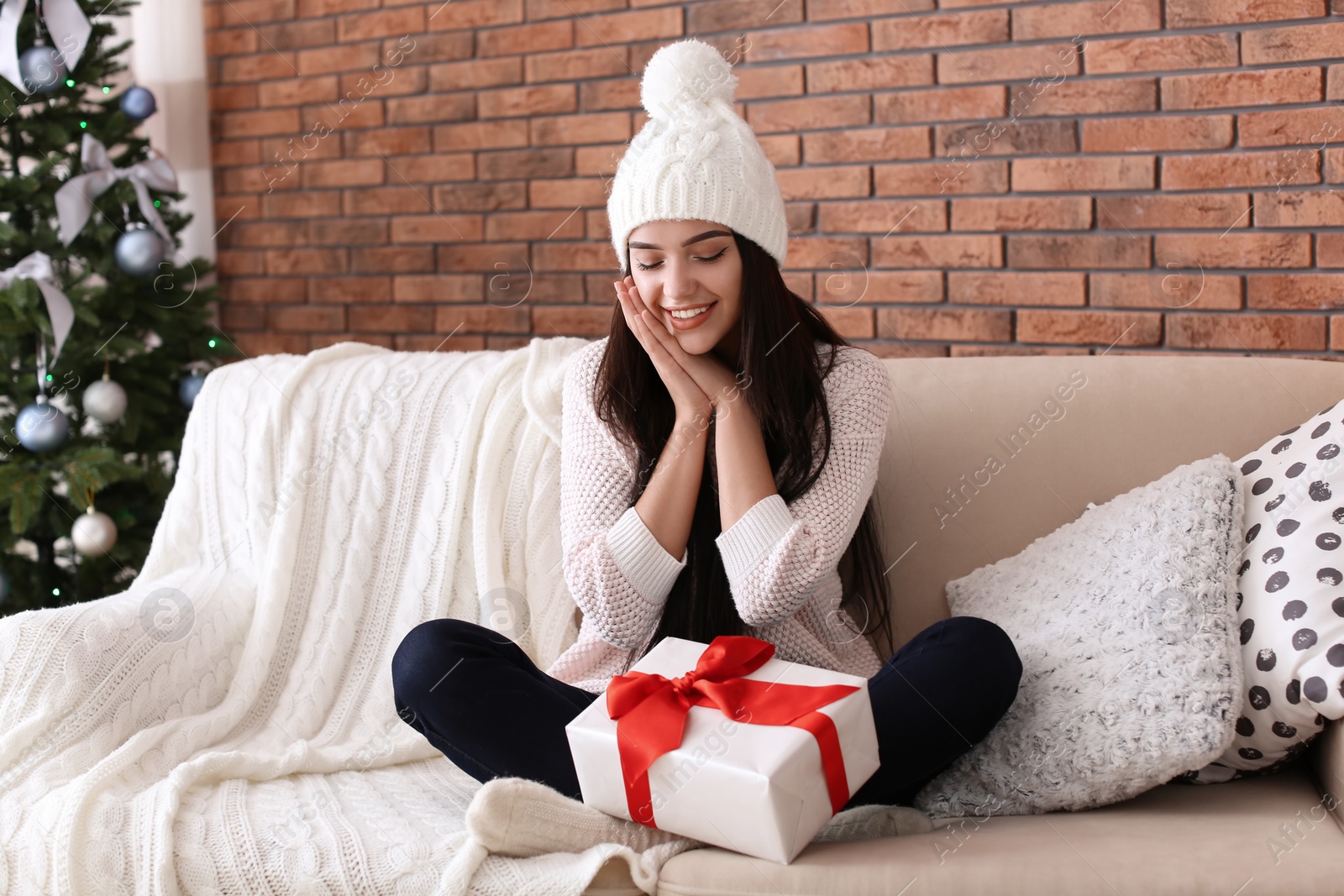 Photo of Beautiful young woman in hat with gift box at home. Christmas celebration