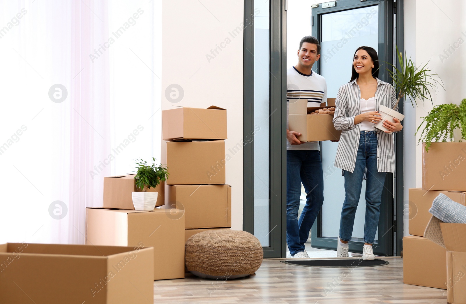 Photo of Happy couple entering their new flat with moving boxes