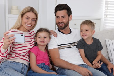 Photo of Happy family taking selfie together on sofa at home