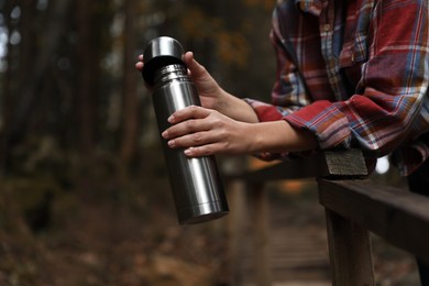 Woman with metallic thermos in nature, closeup