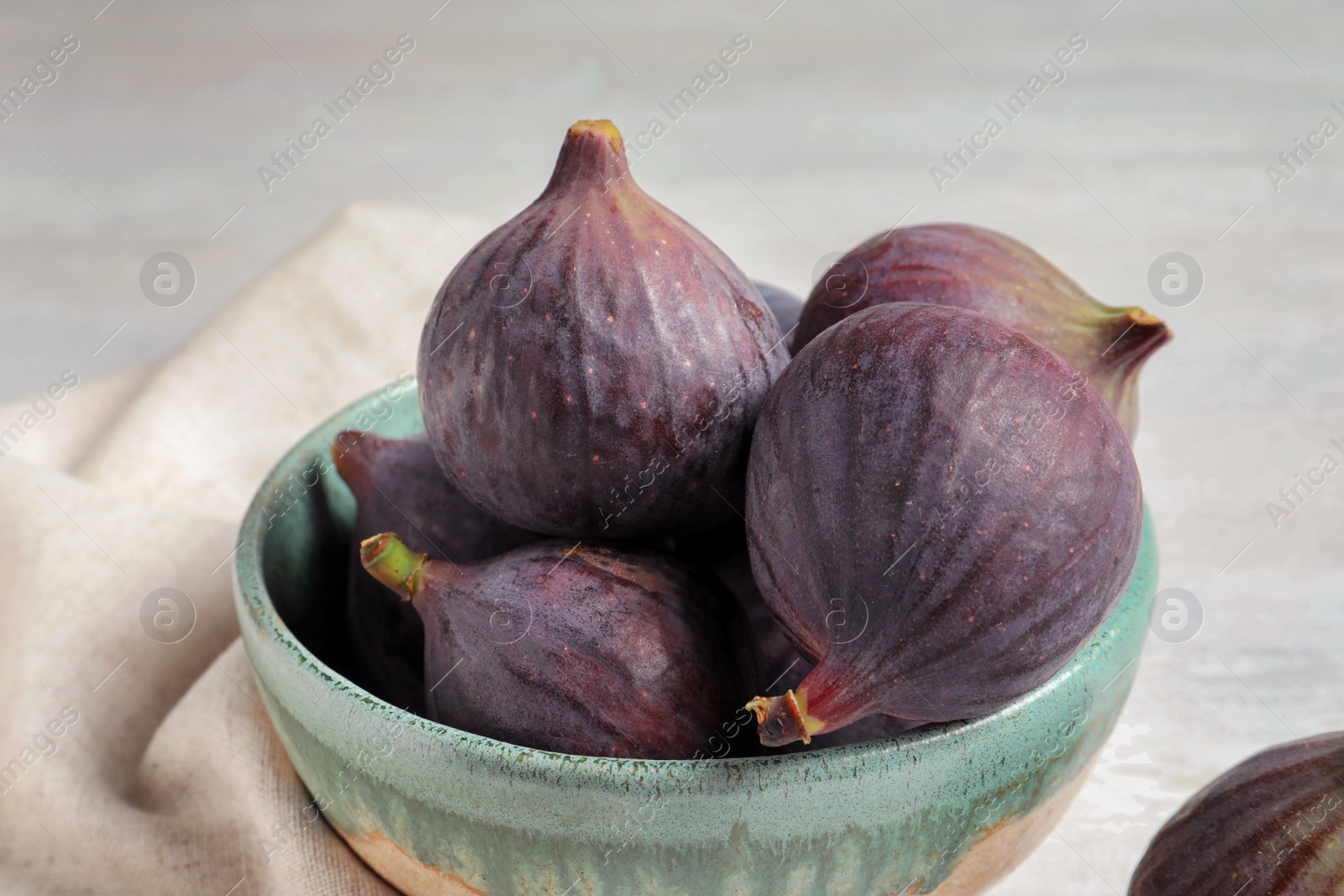 Photo of Bowl with fresh ripe figs on light background. Tropical fruit