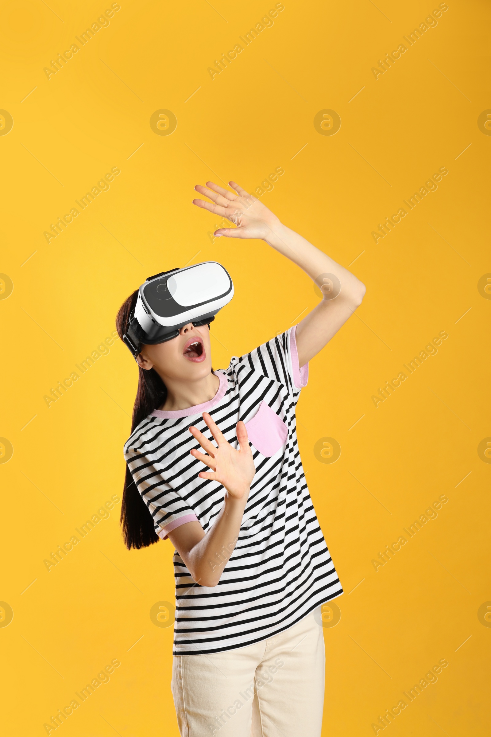 Photo of Woman using virtual reality headset on yellow background