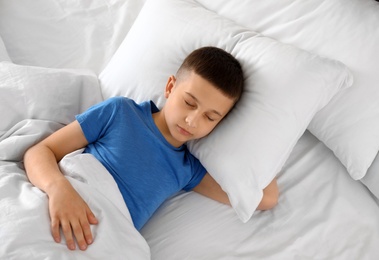 Photo of Portrait of cute boy sleeping in large bed, above view