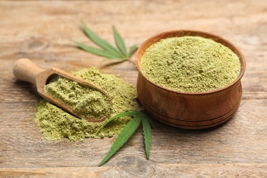 Bowl and scoop of hemp protein powder on wooden table