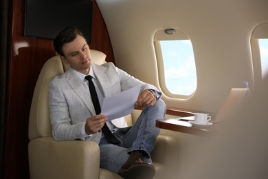 Photo of Businessman working with documents in airplane during flight
