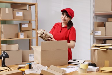 Photo of Post office worker packing parcel at wooden table indoors