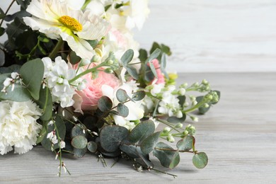 Bouquet of beautiful flowers on light wooden table, closeup