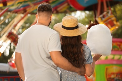 Couple with cotton candy at funfair, back view