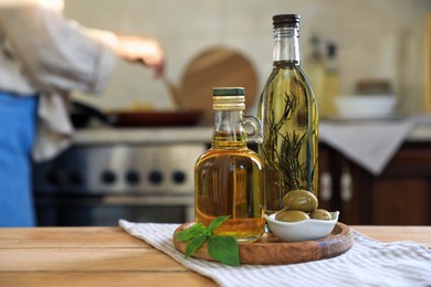 Photo of Different cooking oils and ingredients on wooden table indoors. Space for text