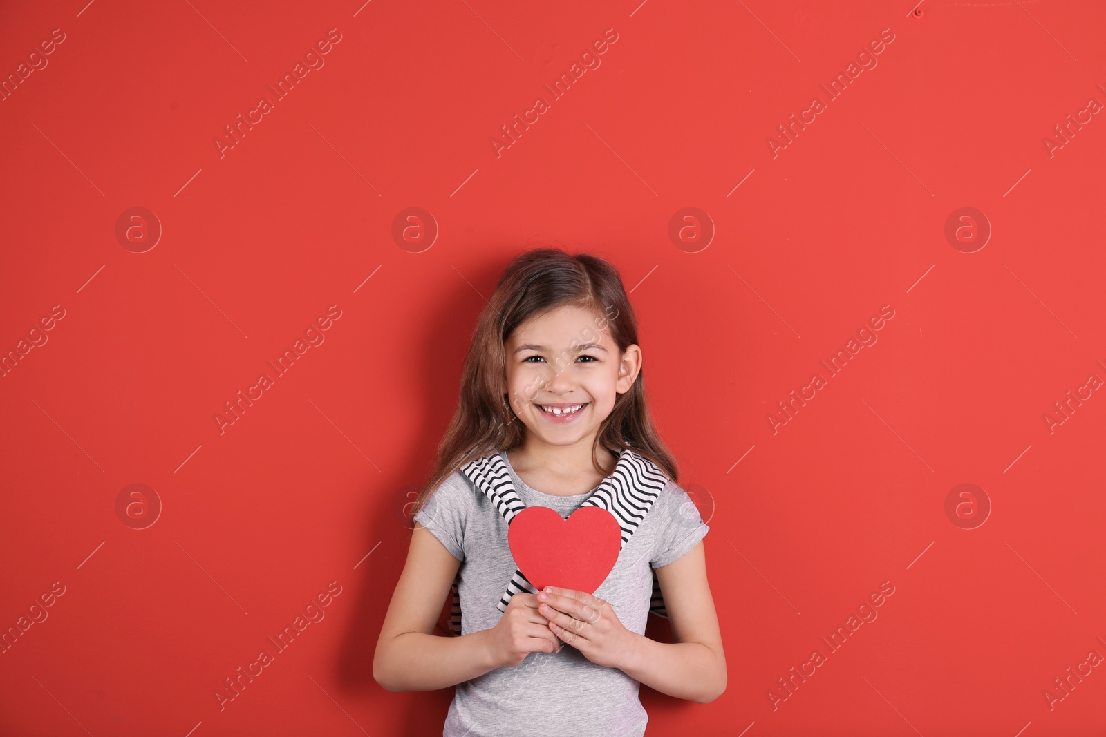 Photo of Portrait of girl with paper heart on color background