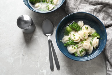 Tasty dumplings in broth served on grey marble table, top view. Space for text