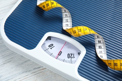 Photo of Scales and measuring tape on wooden background, closeup. Weight loss