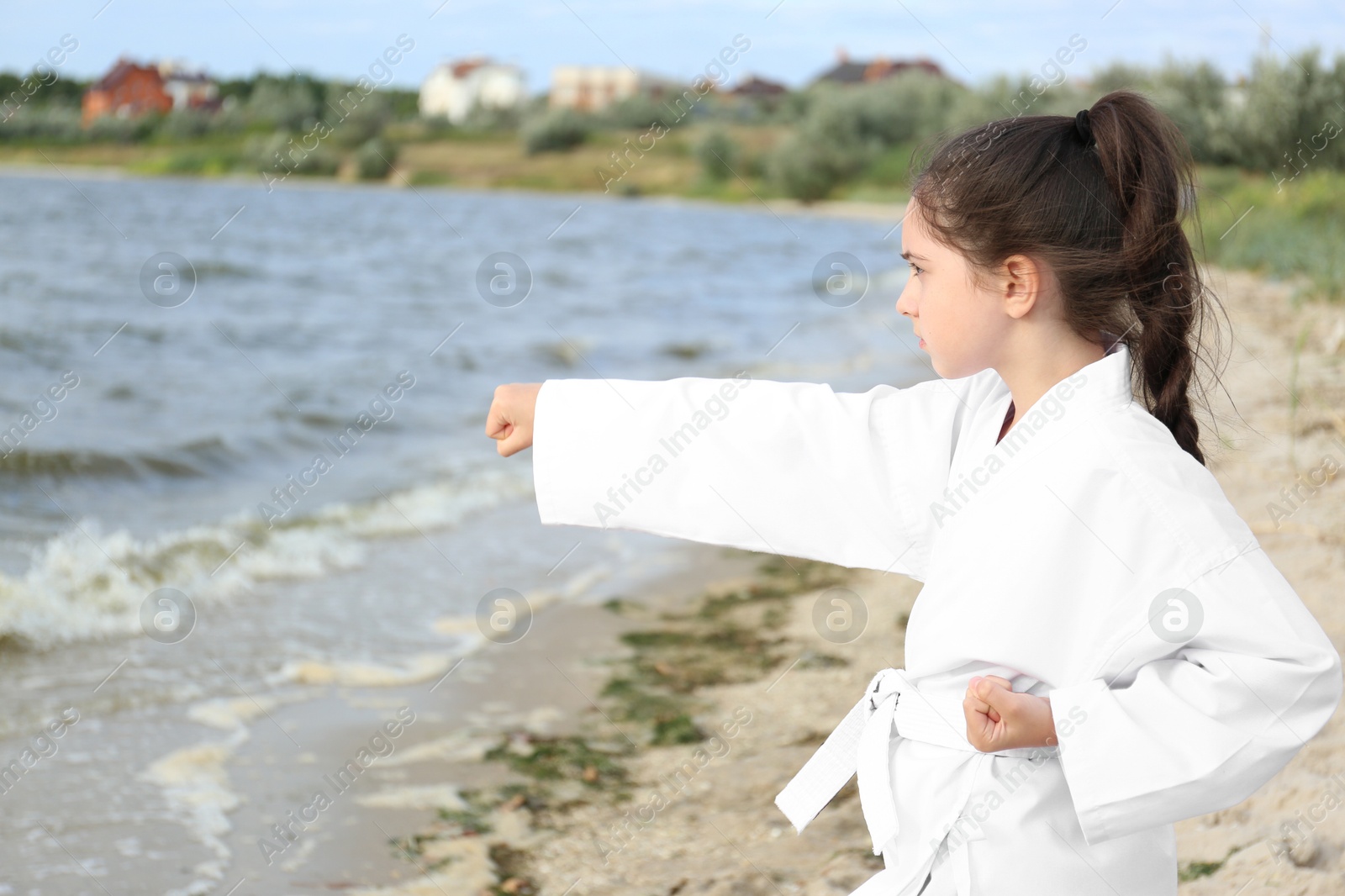 Photo of Cute little girl in kimono practicing karate near river