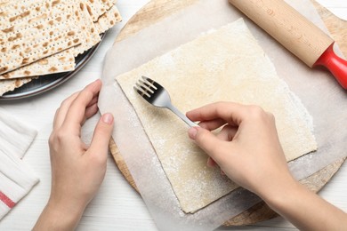Photo of Woman making traditional matzo at white wooden table, top view
