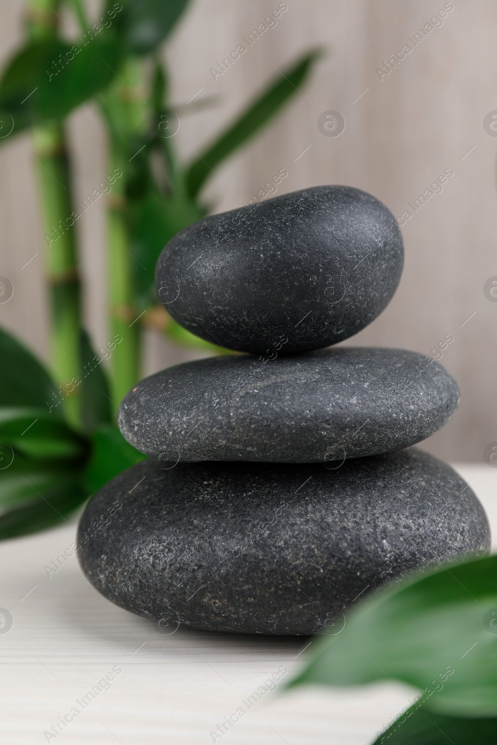 Photo of Stacked spa stones and bamboo on white wooden table, closeup