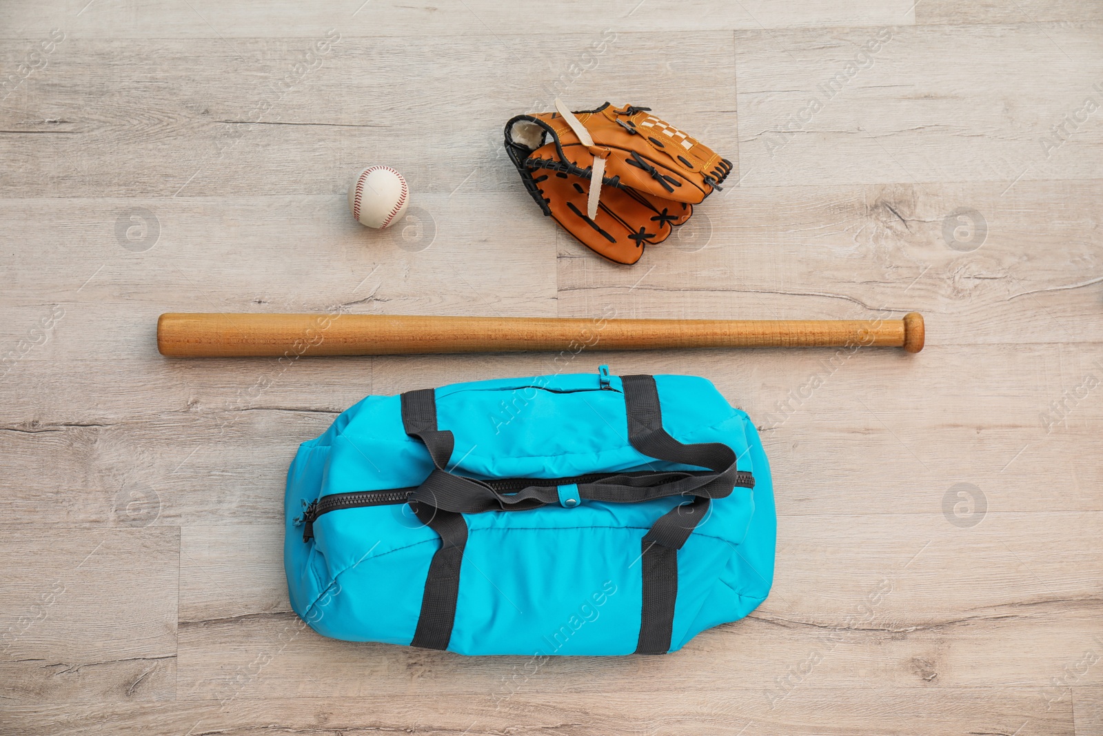 Photo of Sports bag, baseball ball and bat on wooden floor, top view