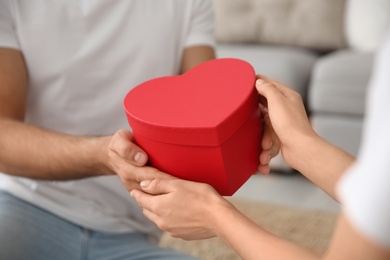 Photo of Man presenting gift to his beloved woman at home, closeup. Valentine's day celebration