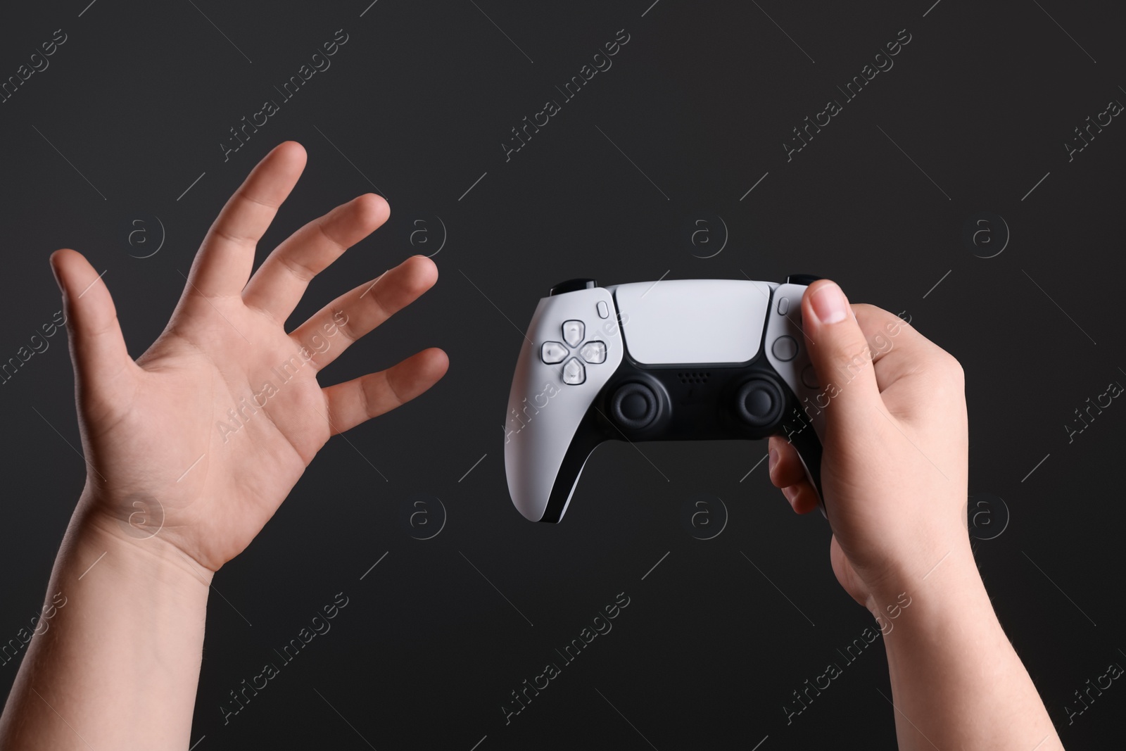 Photo of Woman using wireless game controller on dark background, closeup