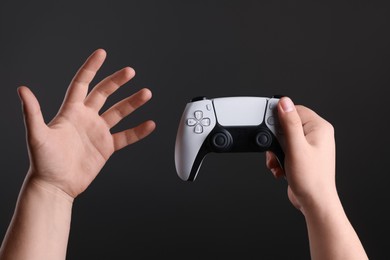 Photo of Woman using wireless game controller on dark background, closeup