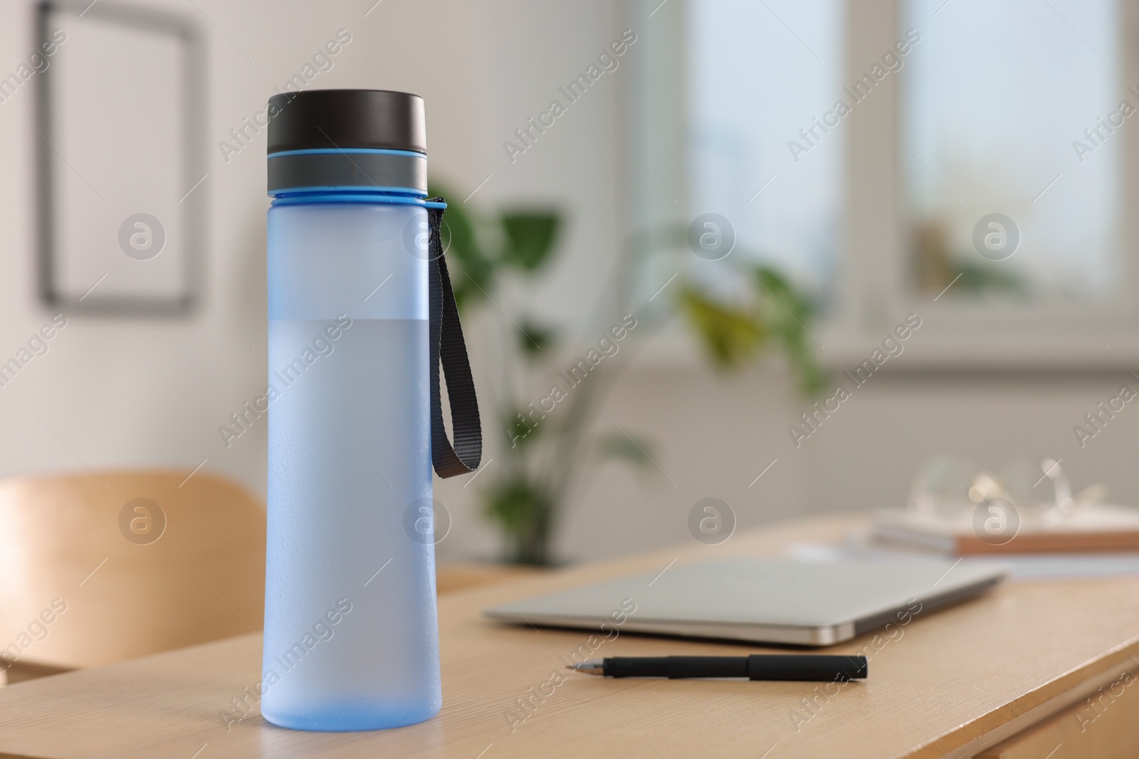 Photo of Transparent bottle at wooden table indoors, space for text